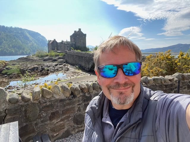 Photo of Marcus standing outside Eilean Donan Castle in Scotland